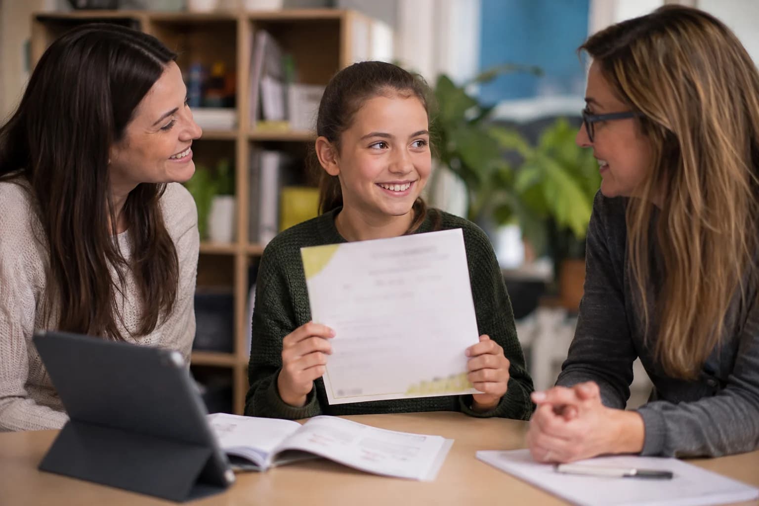 A learner celebrating an achievement with a parent and tutor